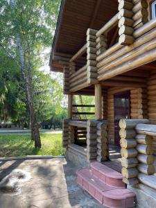 a log cabin with a porch and stairs in a park at Hotel complex Lenivaya Vera in Novaki