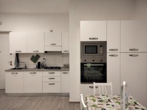 una cucina con armadietti bianchi e forno a microonde di appartamento fronte mare a Pescara