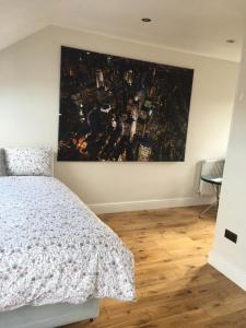 ロンドンにあるTulse Hill Luxury Cosy Roomsのベッドルーム1室(ベッド1台付)が備わります。壁には絵画が飾られています。