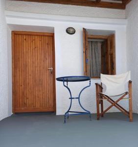 une table et une chaise dans une chambre avec porte dans l'établissement Στη Μεσσάδα... Sti Messada..., à Ioulída