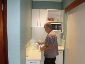a man standing in a kitchen with a microwave at Margaret House in Margaret River Town