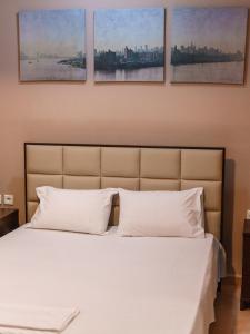 um quarto com uma cama branca com quatro pinturas na parede em Platamon Family Apartments em Platamonas