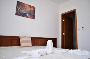 een slaapkamer met een bed met witte handdoeken bij Двустаен апартамент Горски кът Банско in Bansko
