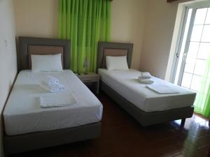 2 camas en una habitación con cortinas verdes en Villa Aroni, en Elafonisos