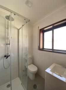 a bathroom with a toilet and a shower and a sink at AMARÉ Guest House in Ovar