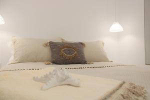 Schlafzimmer mit einem Bett mit weißer Bettwäsche und Kissen in der Unterkunft Plaka Philoxenia Apartments in Plaka Milos