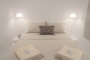 a bed with two pillows and a clock on it at Plaka Philoxenia Apartments in Plaka Milou