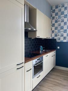 una cocina con armarios blancos y una pared azul en De Malle Molen, en Dinxperlo