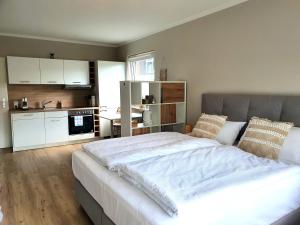a bedroom with a large white bed and a kitchen at Boho Apartment Oldenburg in Oldenburg