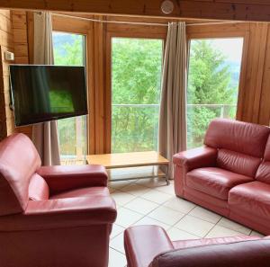 - un salon avec deux chaises et une télévision à écran plat dans l'établissement Chalet chaleureux à Basse-sur-le-Rupt, vue montagne superbe, à Basse-sur-le-Rupt
