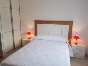 a bedroom with a large white bed with two lamps at Chalet Major Beach Sanxenxo in Sanxenxo