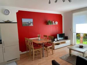 Semi-detached house, Lubmin في لوبمين: غرفة معيشة مع طاولة وجدار احمر
