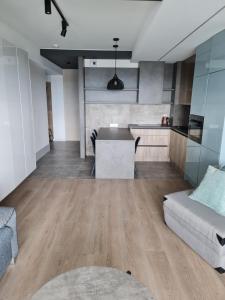 een keuken en een woonkamer met een bank en een tafel bij Porta Mare Apartments LuxView- Budynek Centralny in Dziwnówek