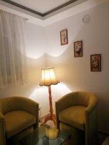 een woonkamer met 2 stoelen, een tafel en een lamp bij Apartmani Glorija in Arandjelovac