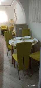 een eetkamer met een tafel en gele stoelen bij Apartmani Glorija in Arandjelovac
