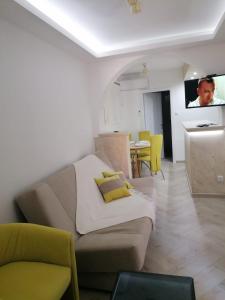 een woonkamer met een bank en een keuken met gele stoelen bij Apartmani Glorija in Arandjelovac