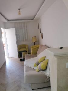 een woonkamer met een witte bank en gele kussens bij Apartmani Glorija in Arandjelovac