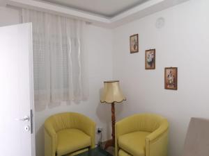 two yellow chairs in a room with a lamp at Apartmani Glorija in Arandelovac
