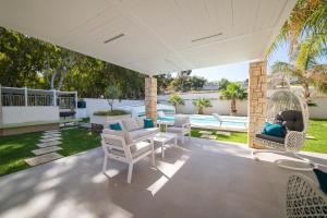een patio met witte stoelen en een tafel bij Villa Perla del Mare in Alcamo Marina