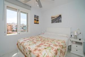 een witte slaapkamer met een bed en een raam bij Piso Manuel Playa Poniente in Benidorm