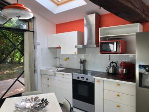 uma cozinha com armários brancos e uma parede vermelha em Chambres & Tables d'Hôtes L'Ostal de Pombonne em Bergerac