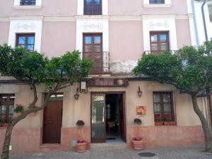 a pink building with trees in front of it at Posada Albarea in Candeleda