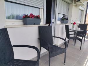 een terras met stoelen en een raam met bloemen erop bij Apartman Sali in Bihać