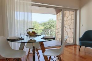 una sala da pranzo con tavolo, sedie e una grande finestra di Varandas de S. Jorge - Apartments a Arcos de Valdevez