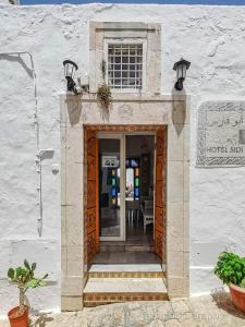 une porte menant à un bâtiment avec une table et des chaises dans l'établissement Hôtel Bou Fares, à Sidi Bou Saïd