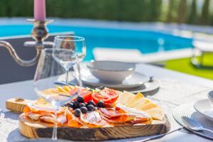 uma mesa com um prato de comida e um copo de vinho em Villa Lumani ** Luxury residence near Split ** em Kučine