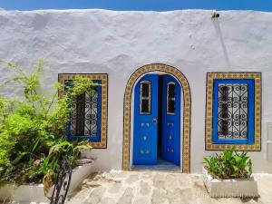 a blue door and two windows on a white building at Hôtel Bou Fares in Sidi Bou Saïd +16 photos