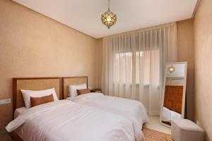 a bedroom with two white beds and a window at Appartement moderne en City Center Marrakech-Gueliz in Marrakech
