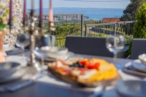 uma mesa com um prato de comida e copos de vinho em Villa Lumani ** Luxury residence near Split ** em Kučine