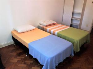 een kamer met drie bedden met verschillende gekleurde lakens bij RIO DE JANEIRO - LEBLON BEACH in Rio de Janeiro