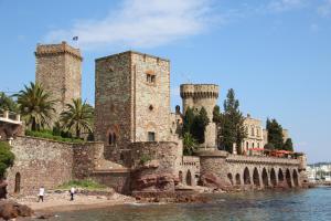 a castle with two towers next to a body of water at Auberge des toqués in Pégomas