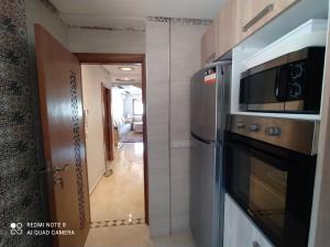 a kitchen with a microwave and a refrigerator and a hallway at Appartement à Bouznika prêt du plage Dahomey, plage bouznika, Bahia beach in Bouznika +20 photos
