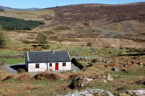 une maison blanche avec des portes rouges sur une colline dans l'établissement Corriebrack cottage, à Hollywood