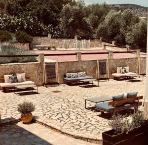 a patio with couches and tables and a stone wall at Elaion mini suites in Nafplio