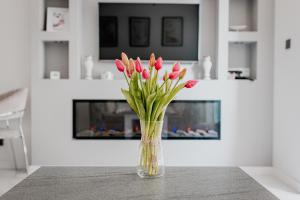 un jarrón lleno de flores rosas sentado en una mesa en Apartament Villa Klar, en Ostróda