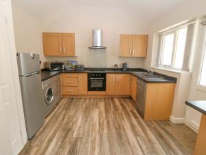 a kitchen with wooden cabinets and a stainless steel refrigerator at St Winifreds in Rhosneigr