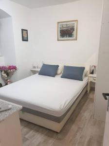 1 cama blanca con almohadas azules en una habitación en apartmani NEDO, en Split