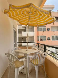 una mesa y sillas con una sombrilla en el balcón en Praia Mar, en Monte Gordo