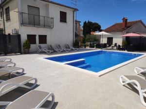 a swimming pool with lounge chairs next to a house at Viktor rooms and apartments in Rovinj