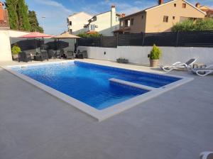 een zwembad met blauw water in een achtertuin bij Viktor rooms and apartments in Rovinj