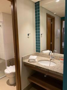 a bathroom with a sink and a toilet and a mirror at Enjoy Solar das Águas Park Resort in Olímpia