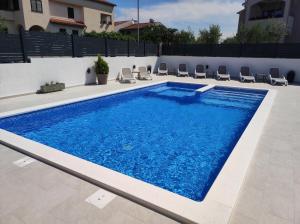 a swimming pool in a backyard with chairs around it at Viktor rooms and apartments in Rovinj