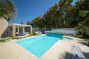 een zwembad in een tuin met een patio en bomen bij Villa Perla del Mare in Alcamo Marina