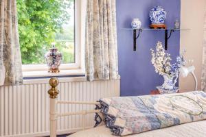 BramhamCabbage Hall Cottage的一间卧室设有一张床和一个带花瓶的窗户