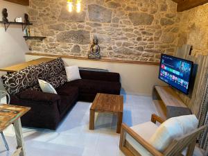 a living room with a couch and a tv at Suleiro de Xusto in Carnota