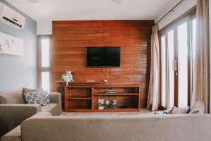 uma sala de estar com uma televisão de ecrã plano numa parede de madeira em Qavi - Pipa Beleza Resort em Pipa